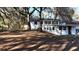 Back exterior view of the home with white brick, mature trees, stairs, and a covered area at 1343 Spring Lake Rd, Fruitland Park, FL 34731