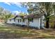 Charming exterior view of a freshly painted white brick home with gray accents and mature trees in the front yard at 1343 Spring Lake Rd, Fruitland Park, FL 34731