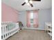 Charming Bedroom featuring a pink accent wall, crib, and window with pink curtains at 157 Primrose Dr, Davenport, FL 33837