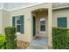 Inviting front entrance featuring decorative shrubs, green shutters, and charming front door at 157 Primrose Dr, Davenport, FL 33837