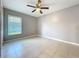 A neutral bedroom featuring a ceiling fan, tile flooring, and a window with natural light at 2732 Lone Feather Dr, Orlando, FL 32837