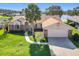 Charming home exterior with a well-manicured lawn, palm tree, and driveway leading to a garage at 2732 Lone Feather Dr, Orlando, FL 32837