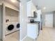Bright kitchen featuring white cabinets, stainless steel appliances, and a laundry closet with a washer and dryer at 2732 Lone Feather Dr, Orlando, FL 32837