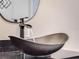 Stylish bathroom sink showcasing a hammered metal basin with a sleek, black faucet and a modern round mirror at 303 Waterwood Dr, Yalaha, FL 34797