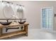 Modern bathroom with double vessel sinks on a wood vanity and a unique glass block window at 303 Waterwood Dr, Yalaha, FL 34797