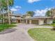 Elegant stucco home with large driveway and three car garage surrounded by large green space and manicured lawn at 303 Waterwood Dr, Yalaha, FL 34797
