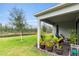 Landscaped backyard featuring a covered patio, mature trees, and a tranquil pond view at 3412 Yellowtop Loop, Clermont, FL 34714