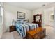 A well-lit bedroom with traditional furniture, a bed with striped bedding, and a peek into an adjacent bathroom at 3412 Yellowtop Loop, Clermont, FL 34714