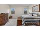 Serene bedroom with neutral tones, natural light from two windows, a wooden chest, and dresser, creating a peaceful space at 3412 Yellowtop Loop, Clermont, FL 34714