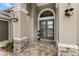 Close up of front door with stone accents, a decorative welcome mat, and stylish lighting fixtures at 534 Two Lakes Ln, Eustis, FL 32726