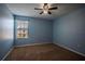 This bedroom features blue walls, a ceiling fan, brown carpet, one window, and electrical outlets at 535 Belle Fern Ct, Ocoee, FL 34761