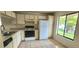 Bright kitchen featuring tile flooring, white appliances, and a large window overlooking the yard at 658 Olympic Dr, Ocoee, FL 34761