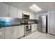 Modern kitchen featuring stainless steel appliances, white cabinets, granite counters, and tiled floors at 6727 Turtlemound Rd # 417, New Smyrna Beach, FL 32169