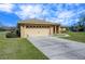 A well-kept home with a concrete driveway leading to an attached two-car garage and manicured front lawn at 7208 Evergreen Loop, Polk City, FL 33868