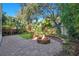 Backyard area featuring brick firepit with beautiful green landscaping at 8149 Via Vittoria Way, Orlando, FL 32819