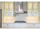 Close-up of white kitchen cabinets, stainless steel hood, gas range, marble countertops and backsplash at 8149 Via Vittoria Way, Orlando, FL 32819