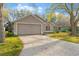 Beige single Gathering home featuring a two-car garage, red door, and simple landscaping at 113 Glasgow Ct, Davenport, FL 33897