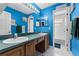 Bright bathroom featuring dual sinks, framed mirrors, wood cabinets and vibrant blue walls at 13506 Crystal River Dr, Orlando, FL 32828