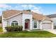Charming home with a well-manicured lawn, arched entry, red front door, and attached two-car garage at 13506 Crystal River Dr, Orlando, FL 32828
