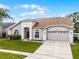 A well-manicured single-story home with a manicured lawn and a two-car garage at 13506 Crystal River Dr, Orlando, FL 32828