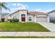 Charming one story home with a well-manicured lawn, a two car garage and a welcoming red front door at 13506 Crystal River Dr, Orlando, FL 32828