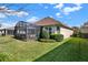Well-maintained backyard featuring a manicured lawn, lush landscaping, and a screened-in patio at 1382 Hayton Ave, Deland, FL 32724