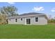 Home backyard featuring a large grassy area, a gray exterior with white framed windows and sliding glass doors at 142 Guava Pass, Ocklawaha, FL 32179