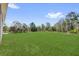 Large grassy backyard with mature trees in the background, surrounded by a partial fence line at 142 Guava Pass, Ocklawaha, FL 32179