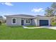 Charming single-story home featuring a blue garage door, fresh lawn, and a modern gray exterior at 142 Guava Pass, Ocklawaha, FL 32179
