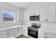 Well-lit kitchen showcasing white cabinets, countertops, and modern stainless steel appliances at 142 Guava Pass, Ocklawaha, FL 32179