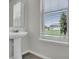 Clean bathroom with a pedestal sink and a bright window offering a view of the landscaped yard at 18058 Cider Mill Ln, Winter Garden, FL 34787