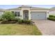 Charming one-story home with a well-manicured lawn, beautiful landscaping, and a brick-paved driveway at 2017 Flora Pass Pl, Kissimmee, FL 34747
