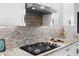 Close-up of the modern kitchen features a gas range, stainless steel hood, and stylish backsplash at 2017 Flora Pass Pl, Kissimmee, FL 34747