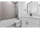 Modern bathroom with tiled shower over tub, white vanity, and gray wood-look flooring at 2436 Sw 155Th Ln, Ocala, FL 34473