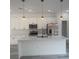 A bright kitchen features white cabinets, modern stainless appliances, kitchen island with a black faucet, and pendant lights at 245 Marion Oaks Golf Rd, Ocala, FL 34473