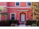 Close up of a pink townhome with a white door, tile awning, and well-maintained landscaping at 3008 Secret Lake Dr, Kissimmee, FL 34747