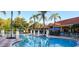 Resort-style pool area featuring crystal-clear water, inviting lounge chairs, and lush landscaping with towering palm trees at 3008 Secret Lake Dr, Kissimmee, FL 34747