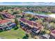 Beautiful aerial view of townhomes with red tile roofs, screened patios, and a serene lake in the community at 3154 Yellow Lantana Ln, Kissimmee, FL 34747