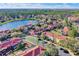 Scenic aerial shot of colorful townhomes with terra cotta roofs surrounding a peaceful lake and lush green landscape at 3154 Yellow Lantana Ln, Kissimmee, FL 34747