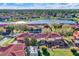 Lovely aerial of townhomes showcasing terracotta roofs, screened patios, lush landscaping and community lake at 3154 Yellow Lantana Ln, Kissimmee, FL 34747