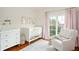 Charming Bedroom with a white crib, dresser, cozy chair, and natural light at 3308 Middlesex Rd, Orlando, FL 32803
