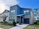 Modern two-story home with a blue exterior, stone accents, a well-manicured lawn and a paver driveway at 8949 Coconut Breeze Dr, Kissimmee, FL 34747