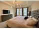 Serene main bedroom features a tray ceiling, modern chandelier, and ample natural light at 8949 Coconut Breeze Dr, Kissimmee, FL 34747