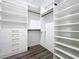 Walk-in closet with custom built-in shelving and dark wood-look floors at 12524 Garrett Pl, Grand Island, FL 32735