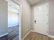 Entryway with front door and view into bedroom with plank flooring and ceiling fan at 12524 Garrett Pl, Grand Island, FL 32735