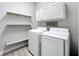 Bright laundry room with white washer and dryer, storage cabinets, and folding shelves at 12524 Garrett Pl, Grand Island, FL 32735