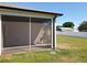 View of the screened porch with concrete floors and white trim, overlooking the manicured lawn at 12524 Garrett Pl, Grand Island, FL 32735