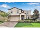 Beautiful two-story home with a well-maintained lawn, brick driveway and lush landscaping at 1454 Belle Terre Rd, Davenport, FL 33896