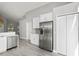 Modern kitchen featuring stainless steel refrigerator, gray backsplash, and white cabinets at 15832 Autumn Glen Ave, Clermont, FL 34714