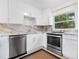 Modern kitchen with sleek white cabinetry, elegant marble countertops, and stainless steel appliances, creating a stylish and functional space at 1632 Pinewood Dr, Orlando, FL 32804